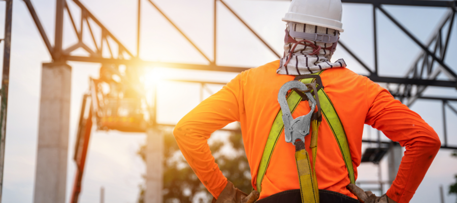 Un travailleur sur un chantier de construction travaillant en hauteur avec un dispositif antichute et des crochets pour un harnais de sécurité.