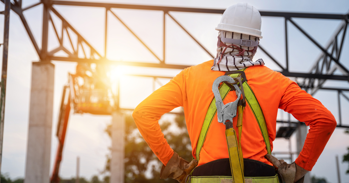 Un travailleur sur un chantier de construction travaillant en hauteur avec un dispositif antichute et des crochets pour un harnais de sécurité.