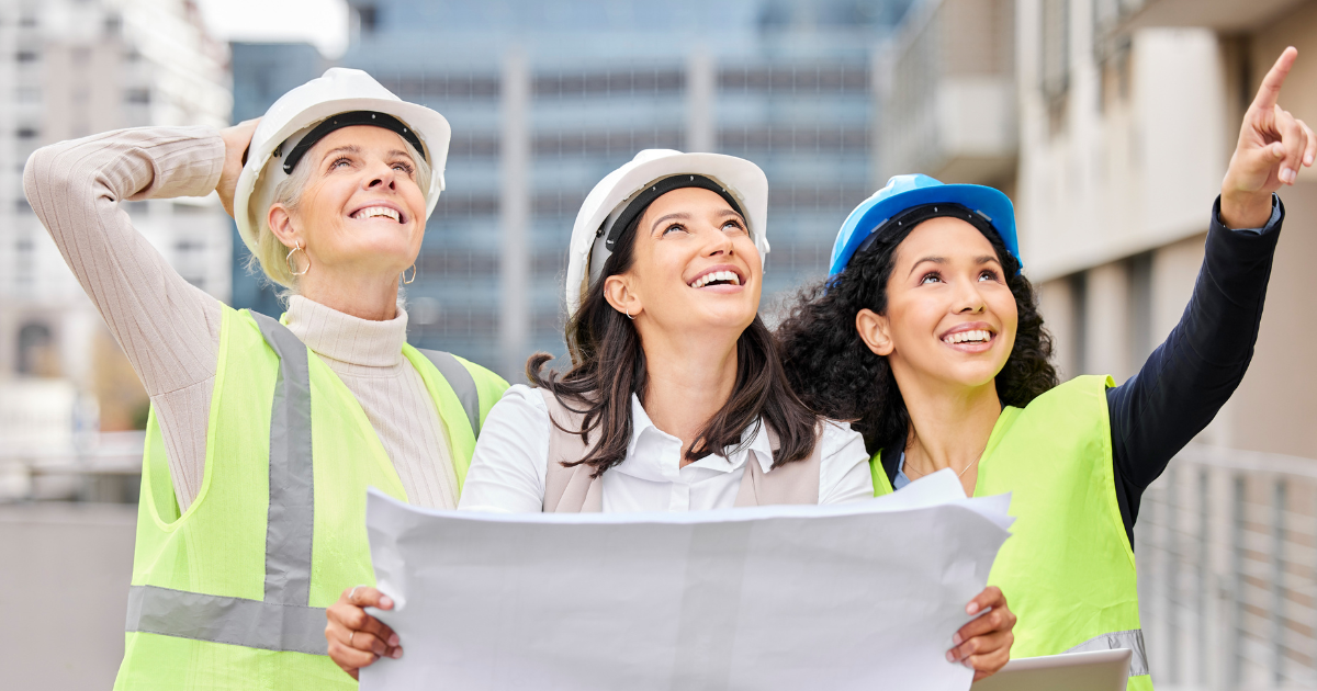 Trois femmes ingénieures en construction analysant un plan sur un chantier, portant des équipements de sécurité. "Les femmes dans les métiers du BTP".