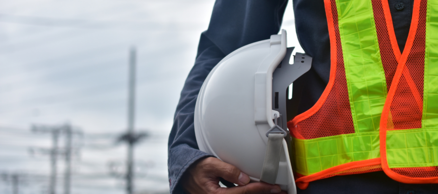 Ingénieur sur chantier tenant un casque de sécurité, supervisant la construction d’un bâtiment.